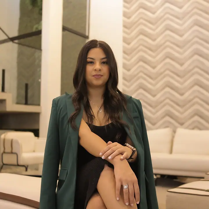 Dra. Akemy Rande de Sousa, de blazer verde, sentada de frente para a câmera em uma sala clara